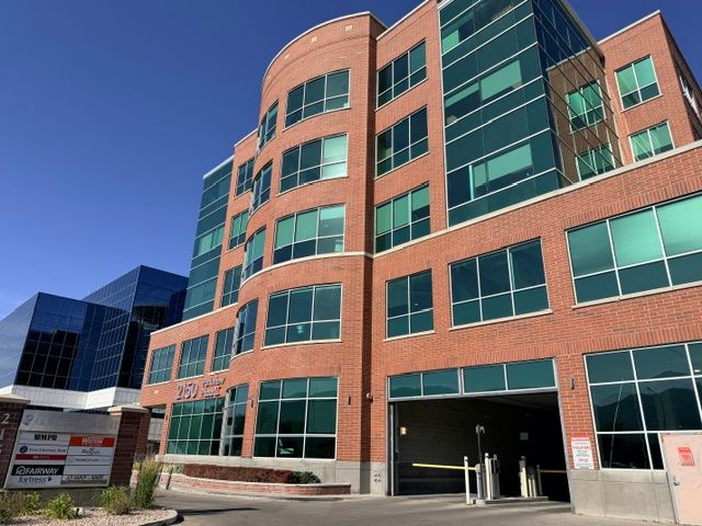 2150 Parkview Plaza II from the street, showing its curved brick corner, tenant directory sign, and covered parking entrance.